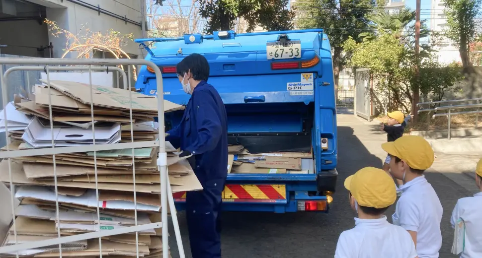 ダンボール回収作業を見学する児童